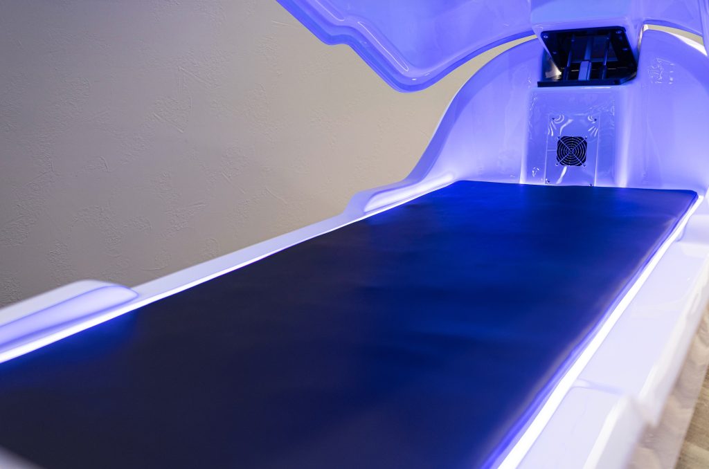 Close-up of the built-in PEMF mat inside the theta chamber at OK Theta & Wellness, illuminated by blue lighting with the chamber lid open.