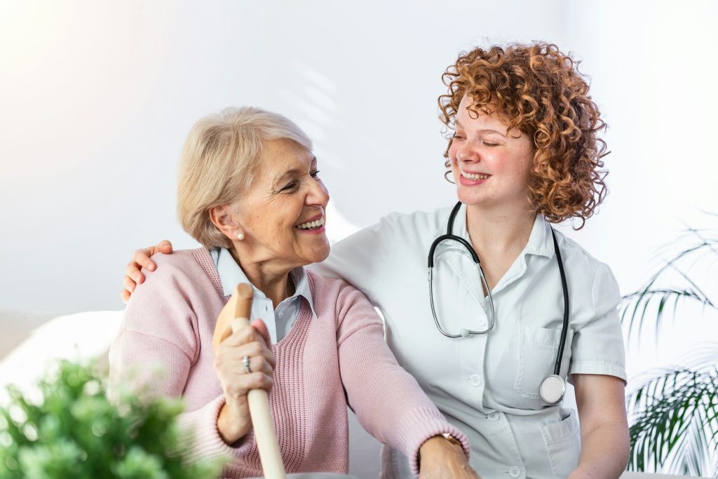 Smiling healthcare provider sitting with an older adult, representing compassionate non-invasive therapy and supportive wellness care.