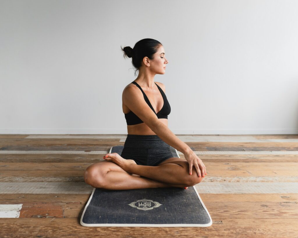 Woman seated on a yoga mat in a gentle spinal twist, illustrating how muscle tightness can involve posture, mobility, breath, and nervous system tension rather than just a shortened muscle.