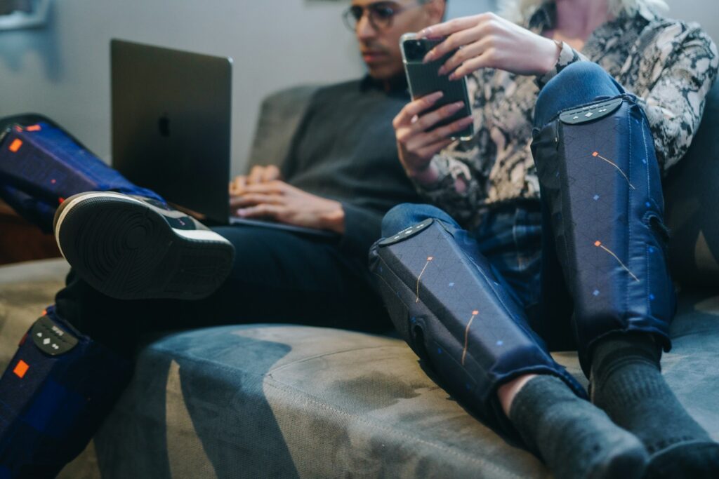 Two people relaxing at home while wearing pneumatic recovery compression boots